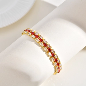 Golden bracelet with three rows of red and white rectangular zircon stones on a white stand