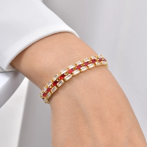 Macro shot of a gold-plated bracelet featuring red and white zircon stones on a model wrist