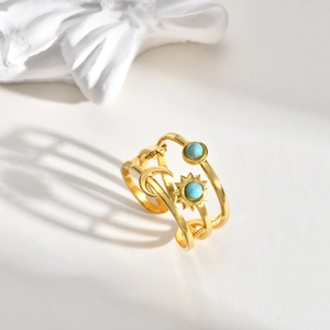 Dettaglio macro dell'anello dorato a più strati con simboli celesti e pietre turchesi