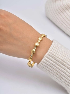 Close-up of golden shell design bracelet with zircon details on a model's wrist