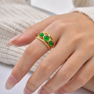 Bague torsadée dorée avec trois pierres vertes portée sur la main d'un mannequin