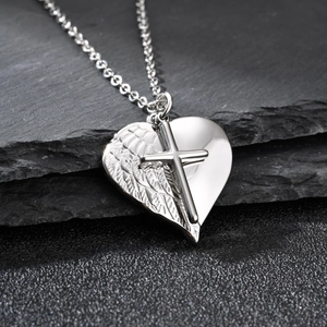 Détail macro du pendentif cœur avec croix et texture d'aile sur fond de pierre noire
