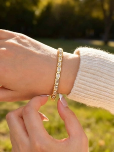 Close-up of a gold-plated bracelet with square-cut cubic zirconia worn on a wrist