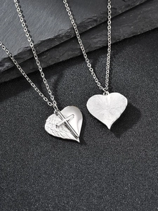 Gros plan de pendentifs cœur en acier avec ailes de croix et texture rayons de soleil