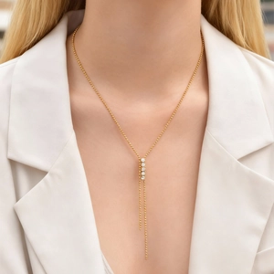 Elegante collana a Y dorata con quattro zirconi bianchi indossata su un abito bianco