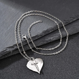 Vue détaillée du pendentif cœur ailes en acier inoxydable argenté avec croix sur pierre