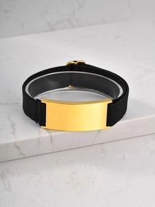 Macro shot of minimalist black elastic strap bracelet with gold polished metal plate for engraving