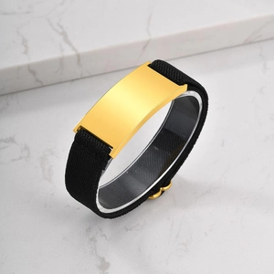 Detail of polished gold ID plate on black elastic band over white marble background