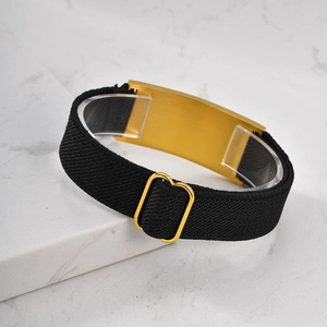 Close-up of golden stainless steel curved plate on black elastic stretch bracelet