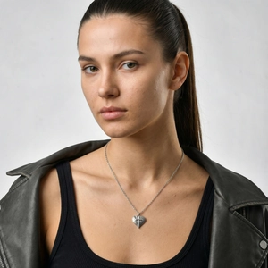 Détail d'un pendentif coeur en acier inoxydable avec croix porté par un mannequin