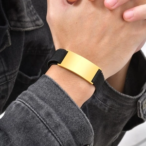 Close-up of a minimalist gold polished metal plate on a black woven elastic strap bracelet