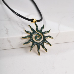 Detail of sun-shaped pendant with dark green enamel and spiral golden hammer texture