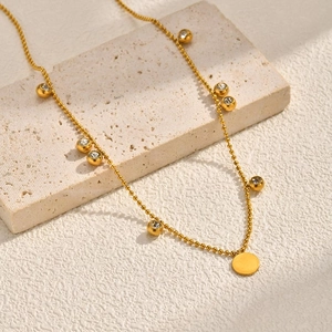 Gold stainless steel beaded necklace with zircon discs on textured stone tray