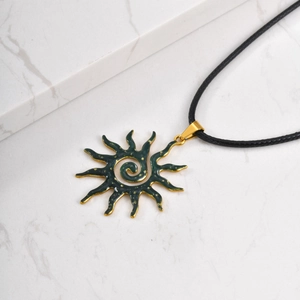 Detail view of retro sun pendant with green hammered enamel and gold finish on marble