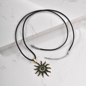 Macro detail of sun pendant with green enamel and spiral texture on marble background