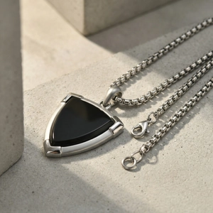 Macro detail of black onyx shield pendant with stainless steel chain on stone