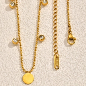 Detailed close-up of 18K gold-plated beaded necklace with zircon discs and lobster clasp