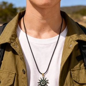 Detailed view of the dark green sunburst pendant with a spiral pattern on a male model