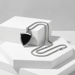Detailed view of silver stainless steel shield pendant with black onyx on marble blocks