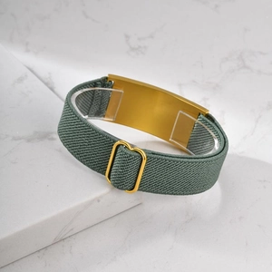 Detail of army green stretch watchband with a smooth gold-plated rectangular metal bar