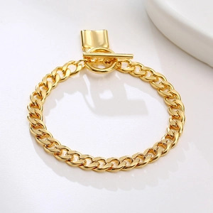 Detailed view of chunky gold chain bracelet with OT toggle clasp and lock charm