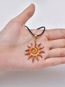 Detail showing the sun pendant with a gradient finish and a black cord necklace