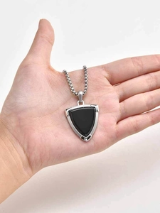 Close-up of a stainless steel shield pendant with black onyx inlay on a metal chain