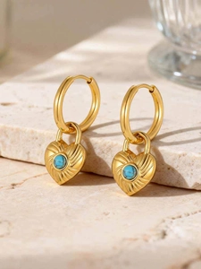 Detail of gold heart lock earrings with turquoise stone on natural stone base