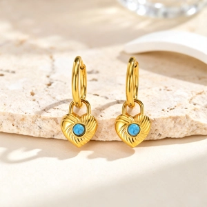 Detailed close-up of heart lock earrings with turquoise stone on stone tray