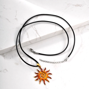 Detailed macro view of sun pendant with orange gradient and spiral design on marble stand