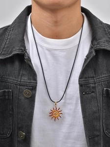 Detail of sun pendant necklace with orange spiral resin on a black leather cord