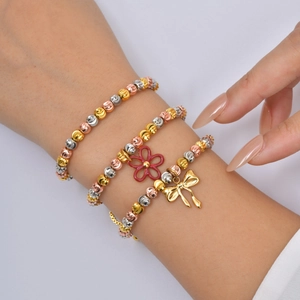 Three-tone beaded bracelet set with flower and bow charms in gold, silver, and rose gold