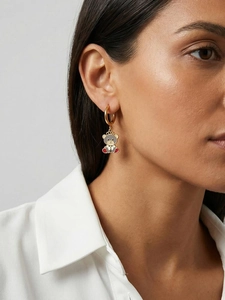 Close-up of golden hoop earring featuring a cute enamel bear pendant worn by a model
