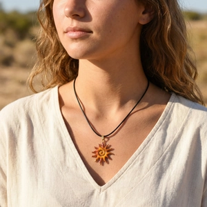 Detail of bohemian sun pendant necklace with orange gradient enamel and gold accents