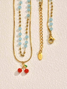 Close-up of golden cherry pendant necklace with blue beads and K18 hallmark detail