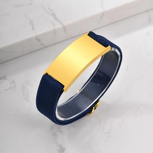 Navy blue elastic woven bracelet with polished gold metal plate on marble background