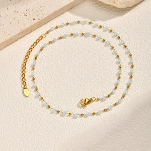 Detail of golden bead necklace with blue sugar cube charms and K18 hallmark tag