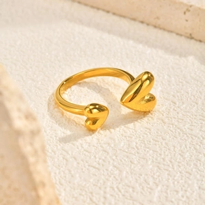 Macro detail of polished gold open heart ring on a white textured stone surface