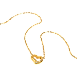 Détail du collier cœur doré orné de zircons blancs sur un fond blanc épuré et élégant
