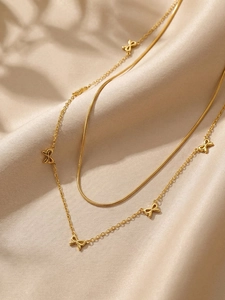 Détail d'un collier double rang doré avec nœuds et chaîne serpent sur fond de soie