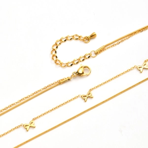 Détail macro du collier double couche doré avec pendentifs nœuds et chaîne serpentine