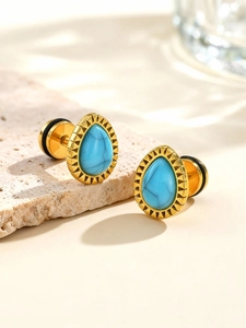 Détail de boucles d'oreilles turquoise en goutte avec bordure dorée texturée sur pierre