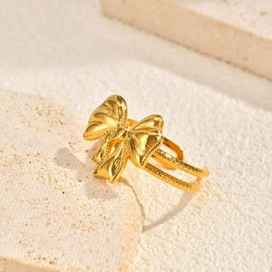 Detailed view of golden double-layered butterfly open ring on travertine background
