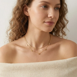 Gros plan du collier double rang doré avec chaîne serpent et cinq pendentifs nœuds