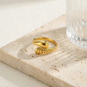 Macro detail of golden teardrop ring featuring spiral texture on a stone pedestal