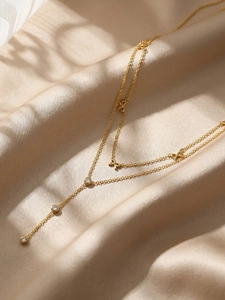 Gros plan du collier nœud doré avec zircons sur un fond de tissu en soie champagne