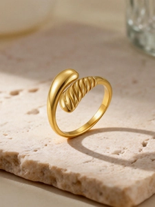Close-up of 18K gold-plated teardrop ring with spiral texture on stone surface