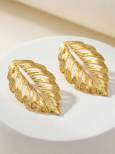 Detailed view of gold hollow leaf earrings on a minimalist stone display stand