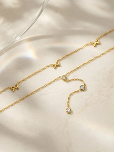 Détail du collier à nœuds dorés avec zircons cubiques sur fond de marbre