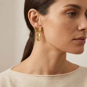 Elegant gold butterfly drop earrings with triple brushed metal layers worn by a model